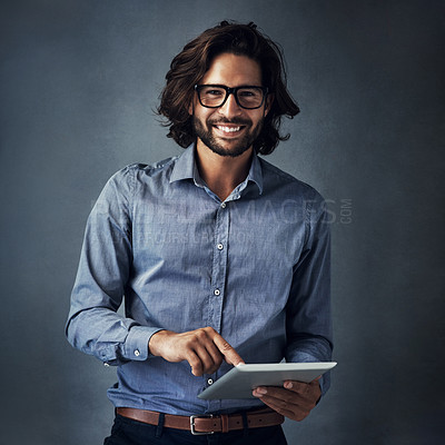 Buy stock photo Studio portrait of a handsome young man using a digital tablet against a gray background
