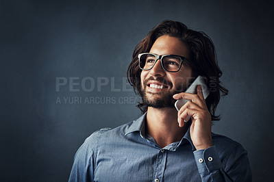 Buy stock photo Studio shot of a handsome young man talking on his cellphone while standing against a grey background