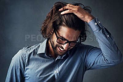 Buy stock photo Studio shot of a handsome young man posing with his hand in his hair against a grey background