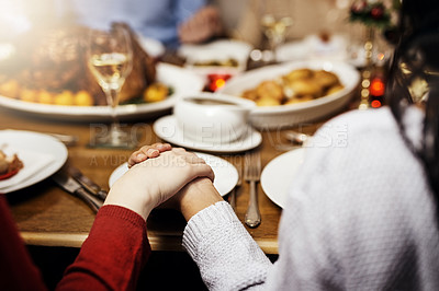 Buy stock photo Cropped shot of unrecognizable people holding hands in prayer before having a Christmas lunch together