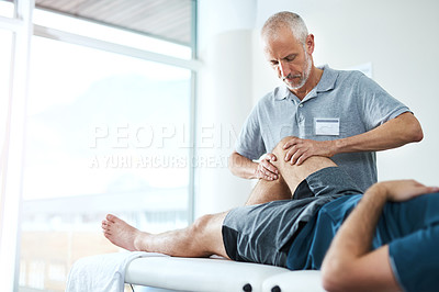 Buy stock photo Cropped shot of a handsome mature male physiotherapist treating an unrecognizable patient