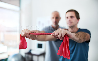 Buy stock photo Cropped shot of a male physiotherapist helping a patient stretch with resistance bands