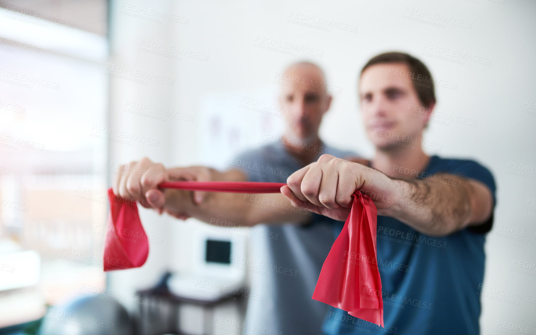 Buy stock photo Cropped shot of a male physiotherapist helping a patient stretch with resistance bands