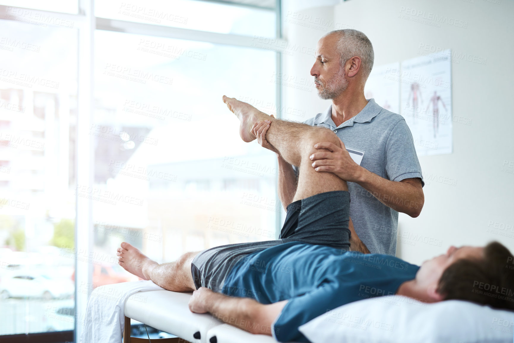 Buy stock photo Cropped shot of a handsome mature male physiotherapist treating a patient