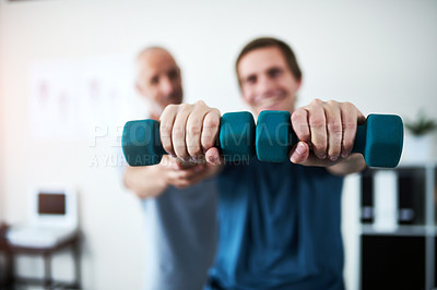Buy stock photo Cropped shot of a mature male physiotherapist helping a patient work through his recovery with weights