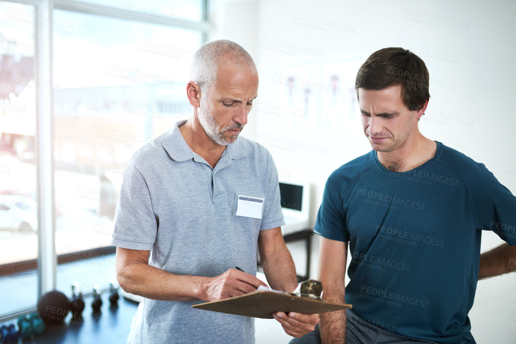 Buy stock photo Men, physiotherapy and patient for rehabilitation with clipboard in pain for checklist, results and report. People, injury and clinic on fitness, exercise and training for wellness and healthcare
