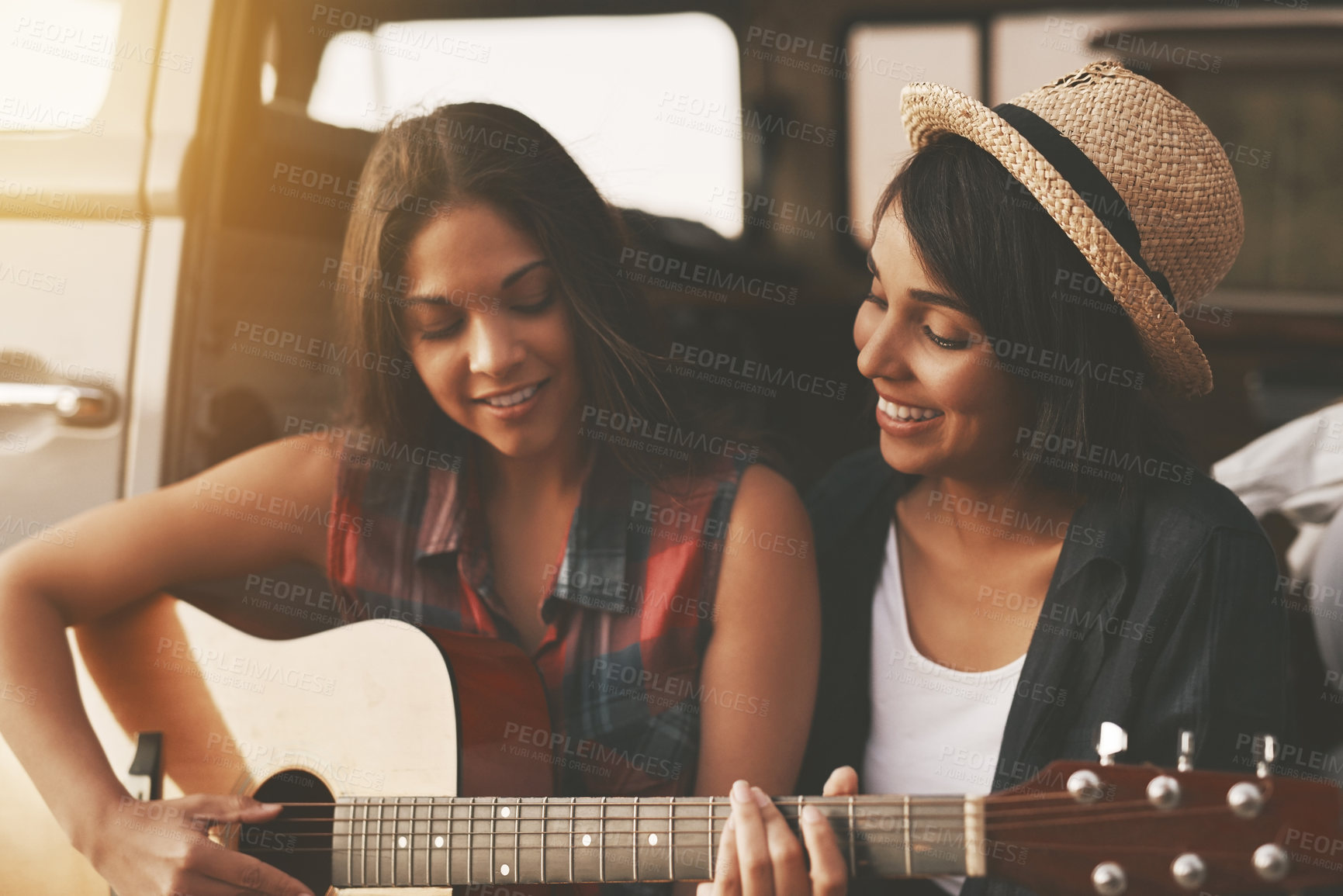 Buy stock photo Friends, guitar and happy for road trip, fun and adventure in van with music, hat or lens flare. Women, hipster and relax for travel, vacation and journey outdoor with smile, singing or song in car