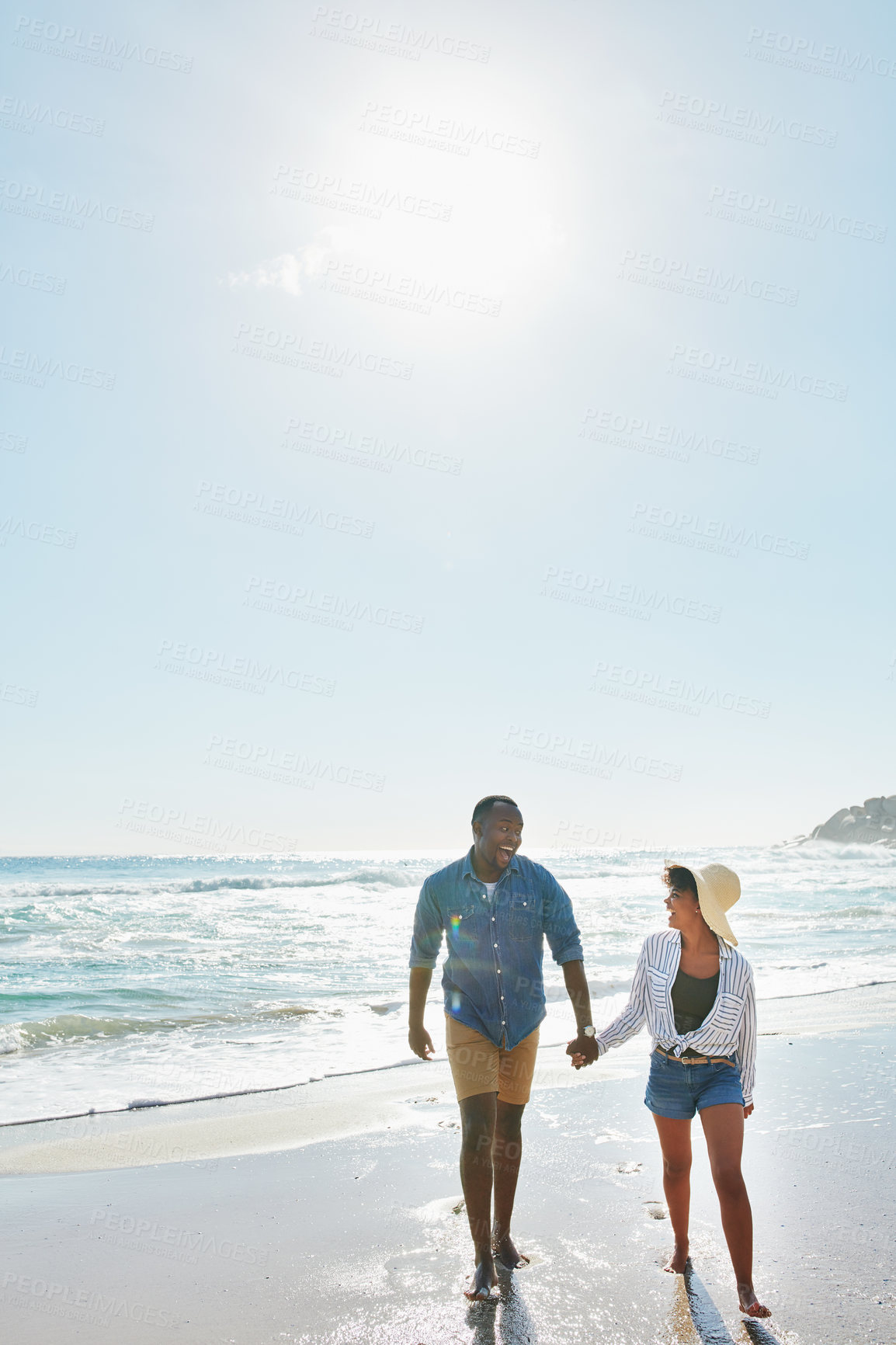 Buy stock photo Black couple, walking and laughing with holding hands on beach for bonding, holiday or outdoor weekend. African man and woman enjoying stroll on sand together for fun summer by ocean coast in nature