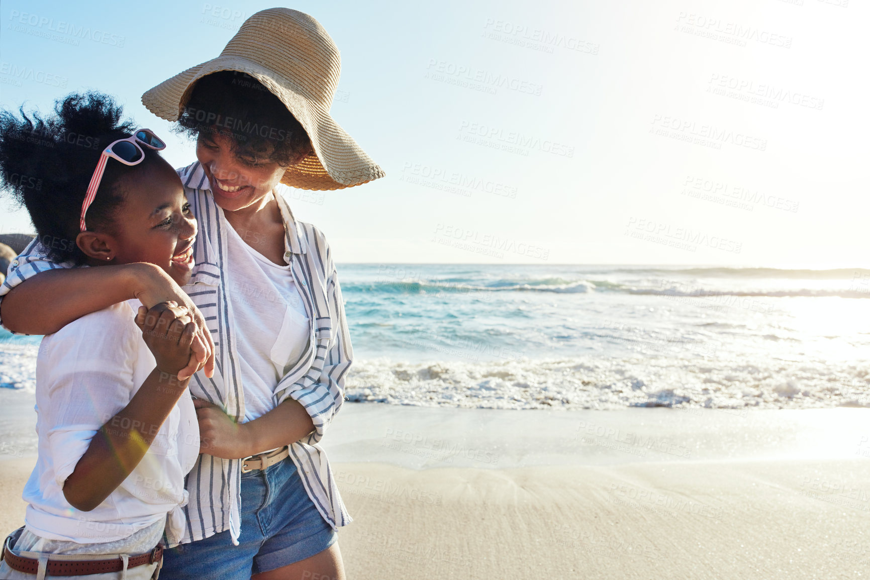 Buy stock photo Black mother, hug and walking with daughter on beach for bonding, holiday or outdoor weekend. African mom, child or kid with smile for family time or summer day together by ocean coast in nature