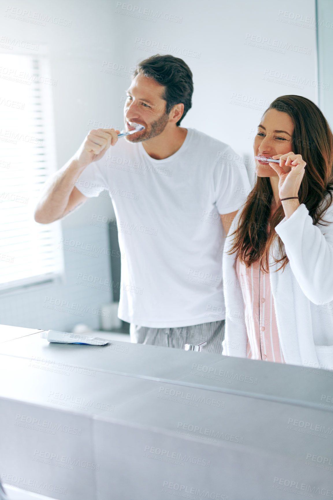 Buy stock photo Brushing teeth, morning and toothbrush with couple in bathroom for oral hygiene, breath and cleaning. Self care, wellness and dental with man and woman at home for gum treatment, toothpaste or health