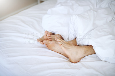 Buy stock photo Cropped shot of a couple's feet as they lay in bed together