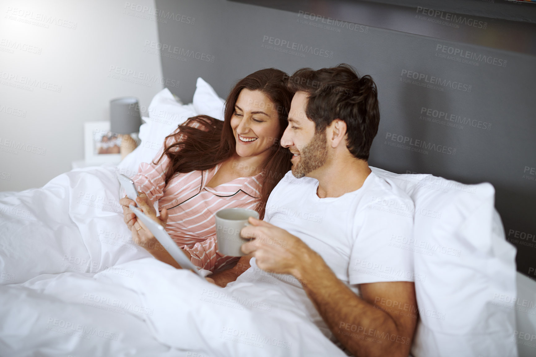 Buy stock photo Phone, tablet and couple in bed in house scrolling, browsing and networking on social media in morning. Coffee, digital technology and cellphone with man and woman relaxing in bedroom at home.