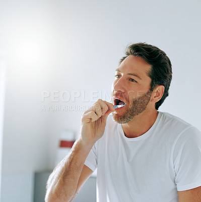 Buy stock photo Cropped shot of a handsome middle aged man brushing his teeth in the bathroom at home
