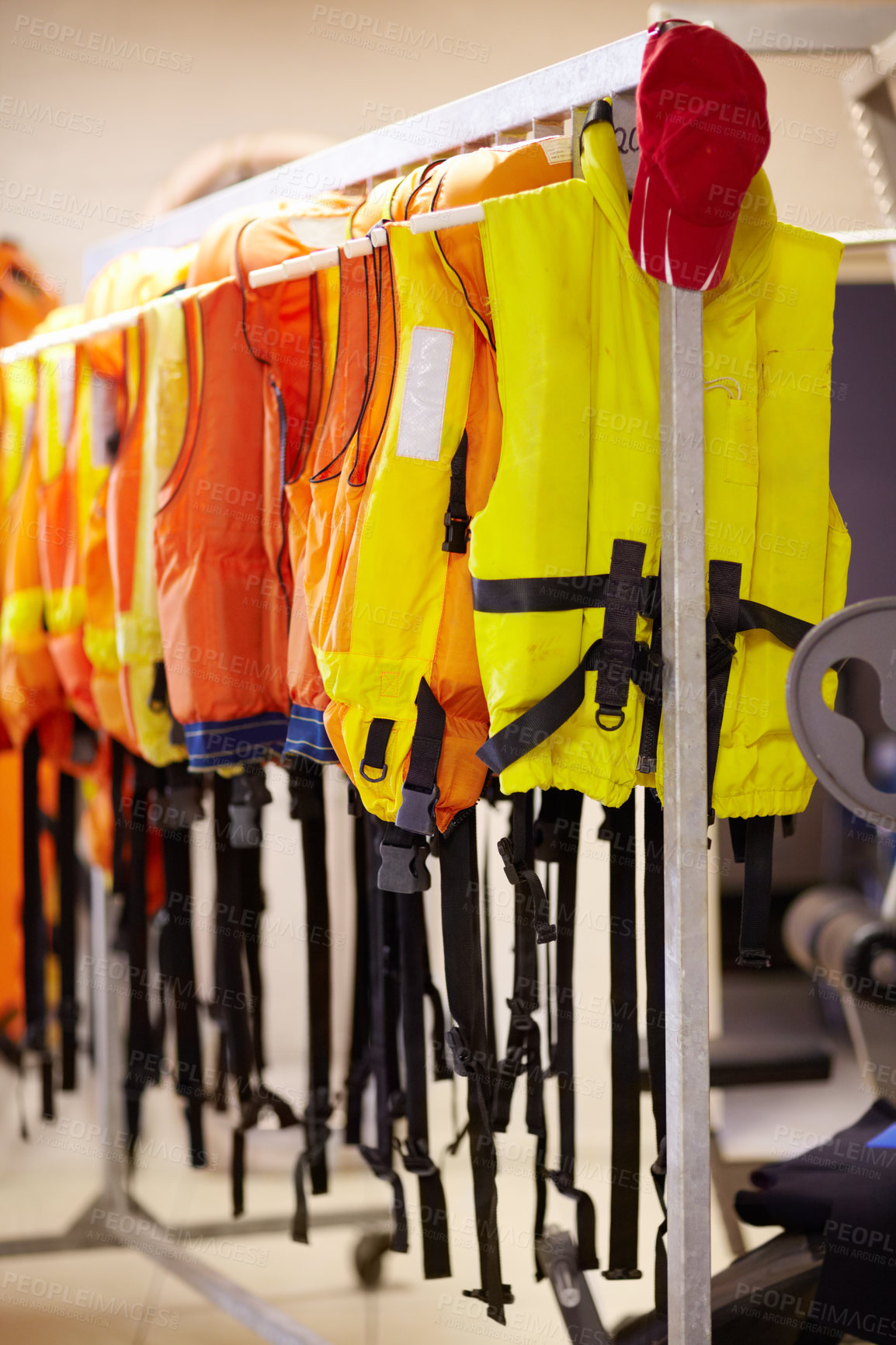 Buy stock photo Cropped shot of life jackets hanging on a rail inside a lifeguard station