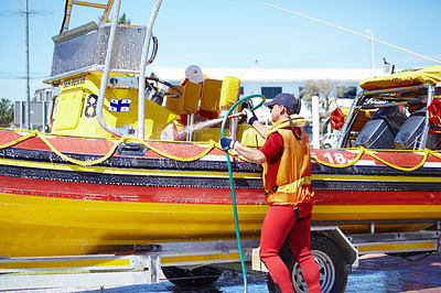 Buy stock photo Cropped shot of a handsome young male lifeguard cleaning the boat after a rescue mission