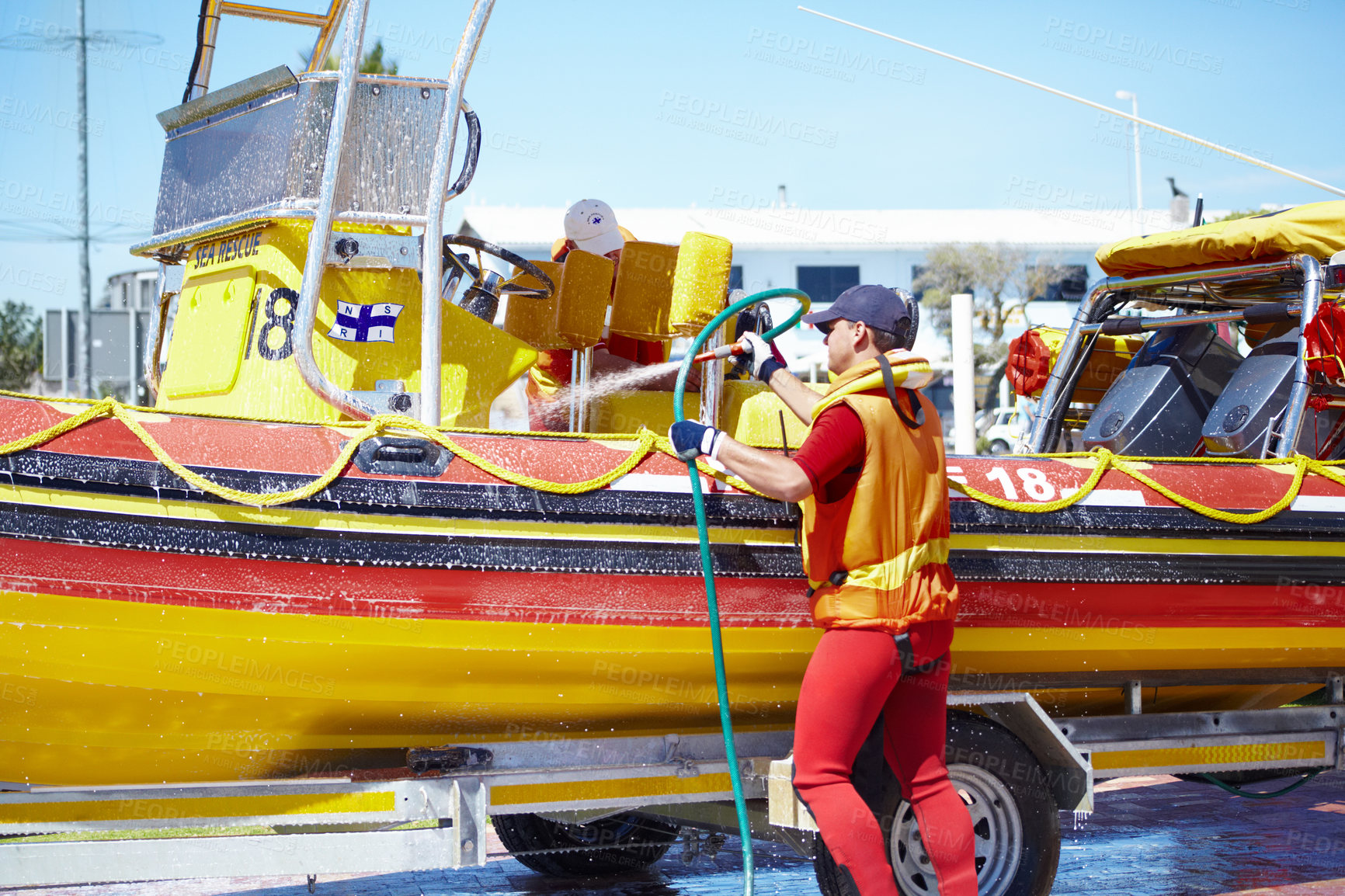 Buy stock photo Cropped shot of a handsome young male lifeguard cleaning the boat after a rescue mission