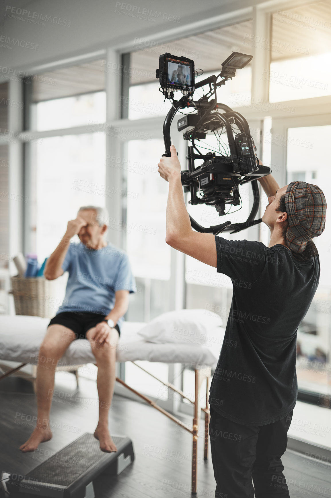 Buy stock photo Man, videographer and producer with camera for recording, online vlog or filmaking at studio. Male person, photographer or director with elderly patient for behind the scenes, tutorial or production