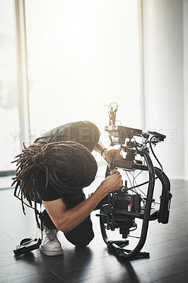 Buy stock photo Man, equipment and camera operator in film or media production for shoot, script or brief in studio. Male person, technology and behind the scenes as videographer for cinema, broadcast or advertising