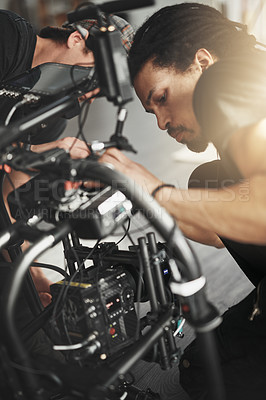 Buy stock photo Behind the scenes shot of a videographer working on a state of the art video camera inside of a studio during the day