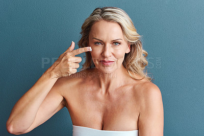 Buy stock photo Studio portrait of an attractive mature woman applying moisturizer against a grey background