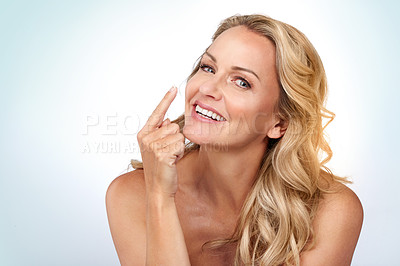 Buy stock photo Studio portrait of an attractive mature woman applying moisturizer against a grey background