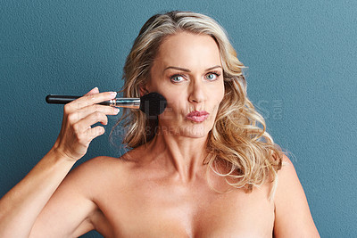 Buy stock photo Studio portrait of an attractive mature woman applying blusher against a grey background