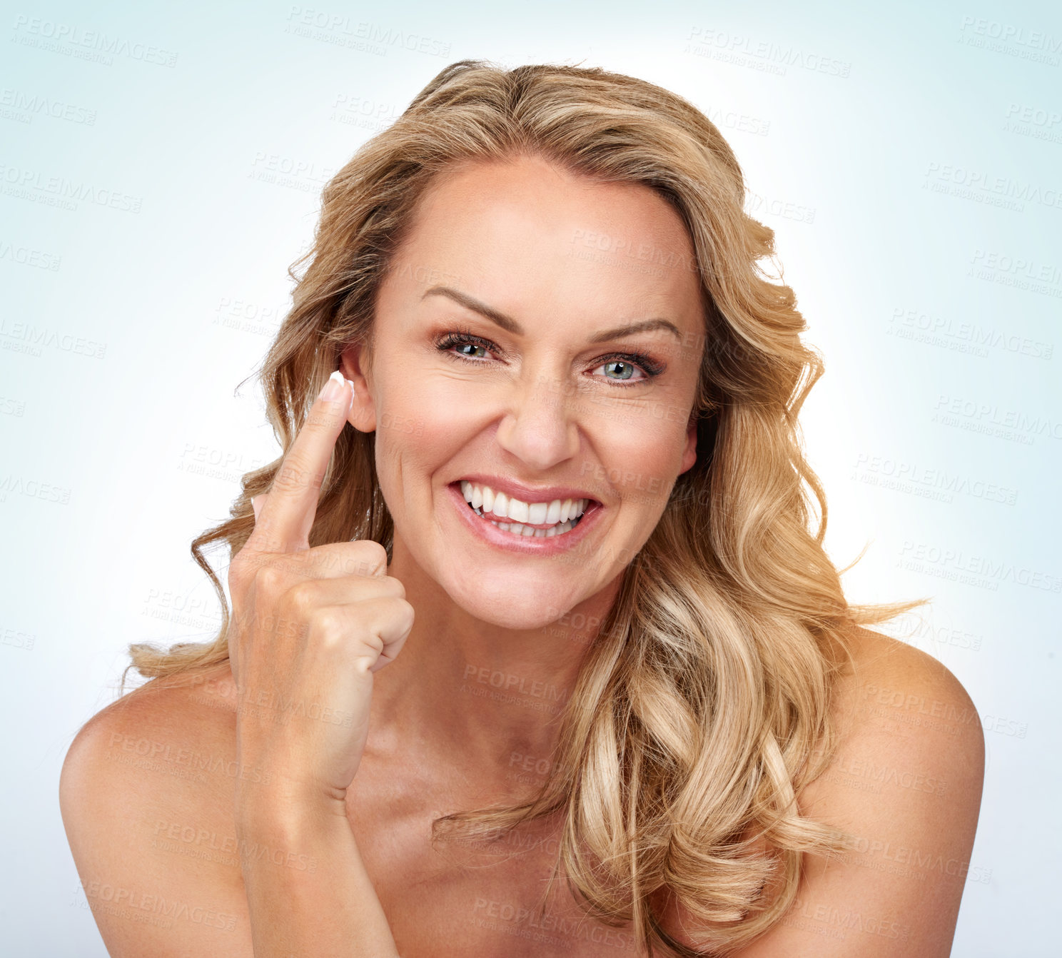 Buy stock photo Studio portrait of an attractive mature woman applying moisturizer against a grey background