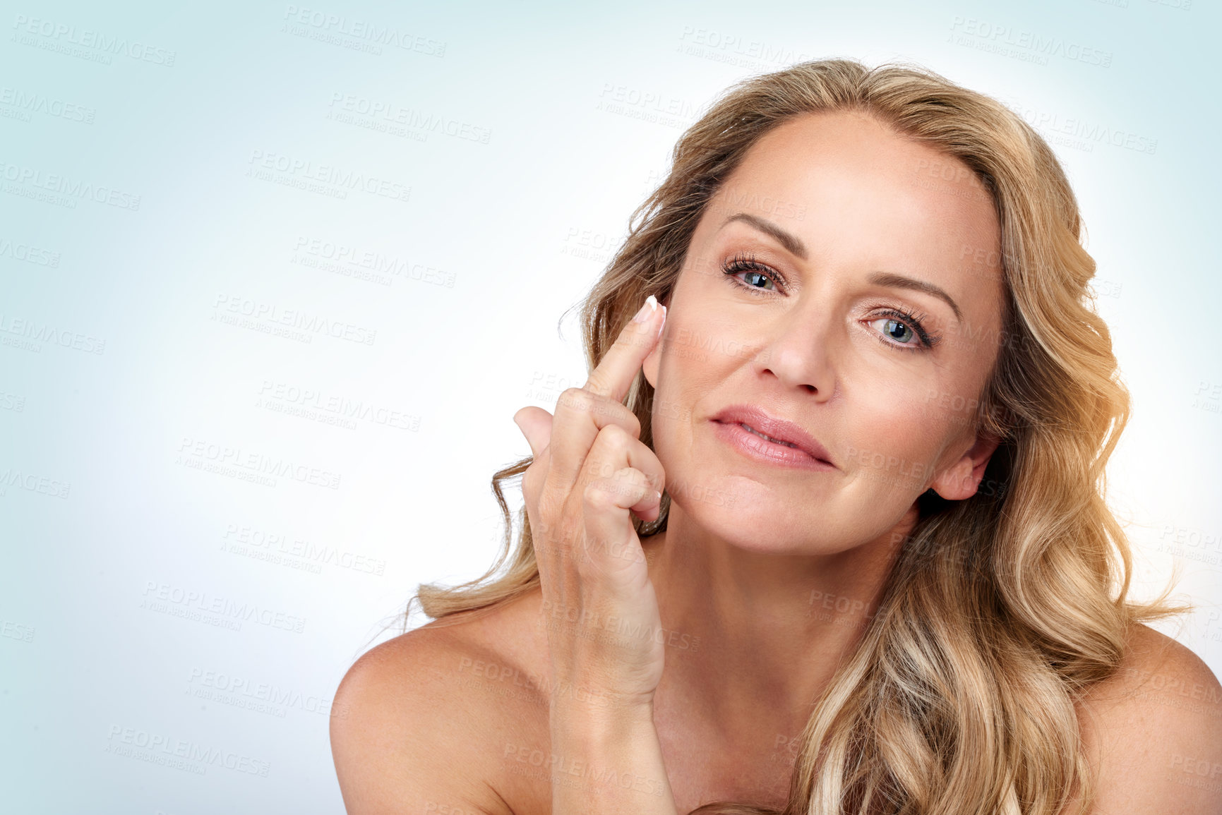 Buy stock photo Studio portrait of an attractive mature woman applying moisturizer against a grey background