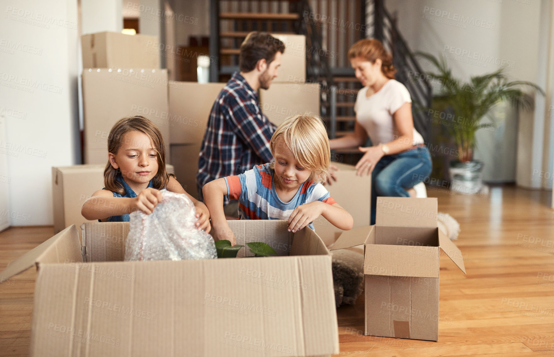 Buy stock photo Boxes, new home and parents with kids, playing and bonding together with property. Happy family, apartment and cardboard with mother, father and childhood with real estate, cheerful and moving