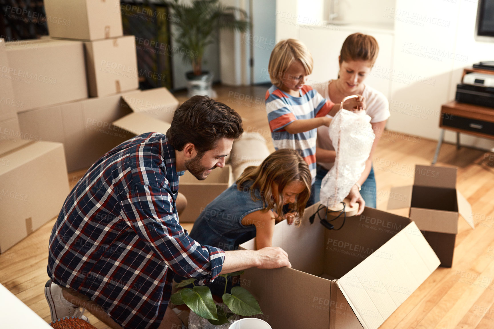 Buy stock photo Boxes, new home and parents with kids, help and bonding together with real estate. Happy family, apartment and cardboard with mother, father and childhood with property, cheerful and moving in lounge