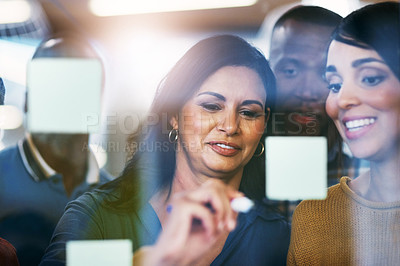 Buy stock photo Shot of a group of businesspeople brainstorming with notes on a glass wall in an office