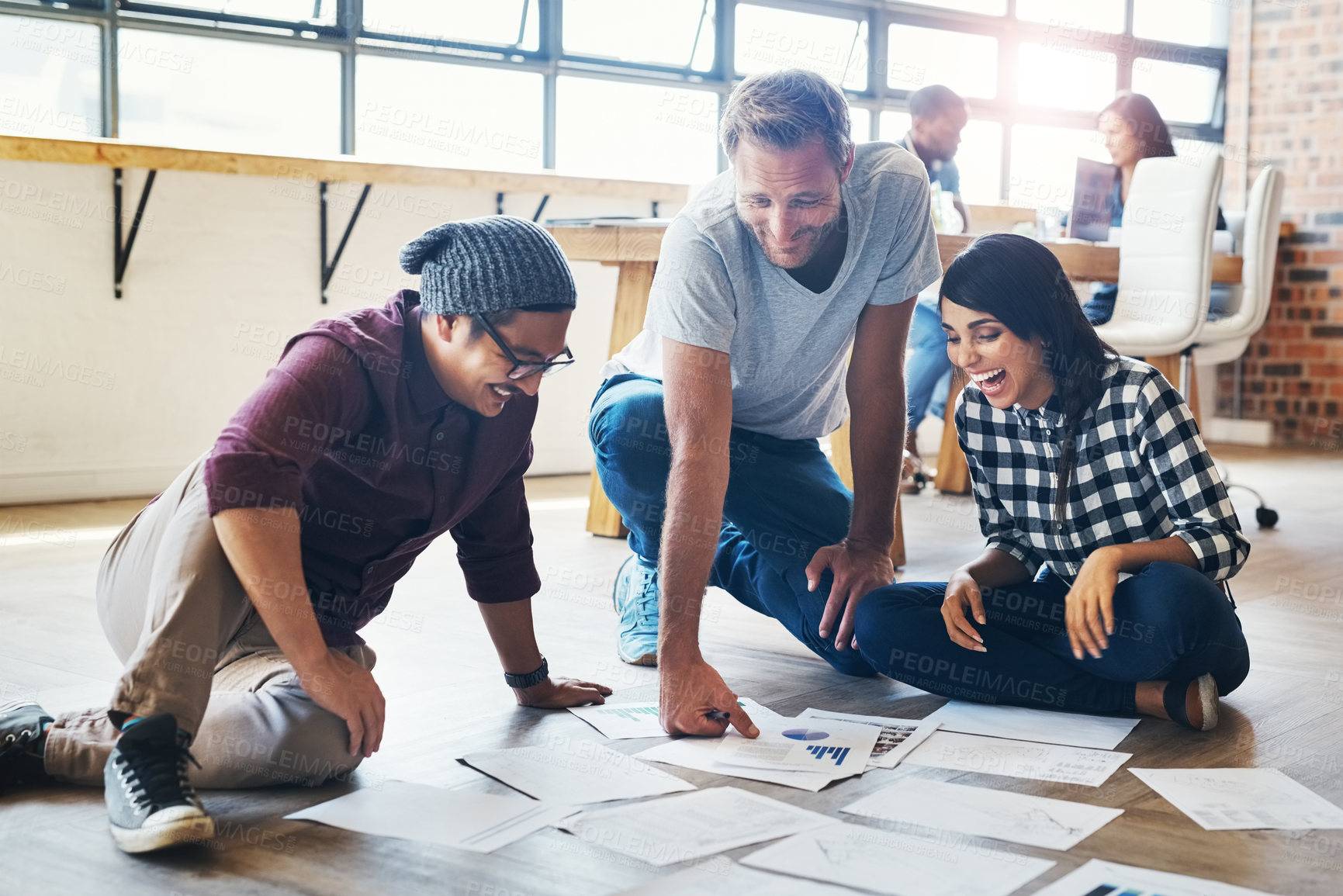 Buy stock photo Shot of a group of businesspeople brainstorming on the floor in an office