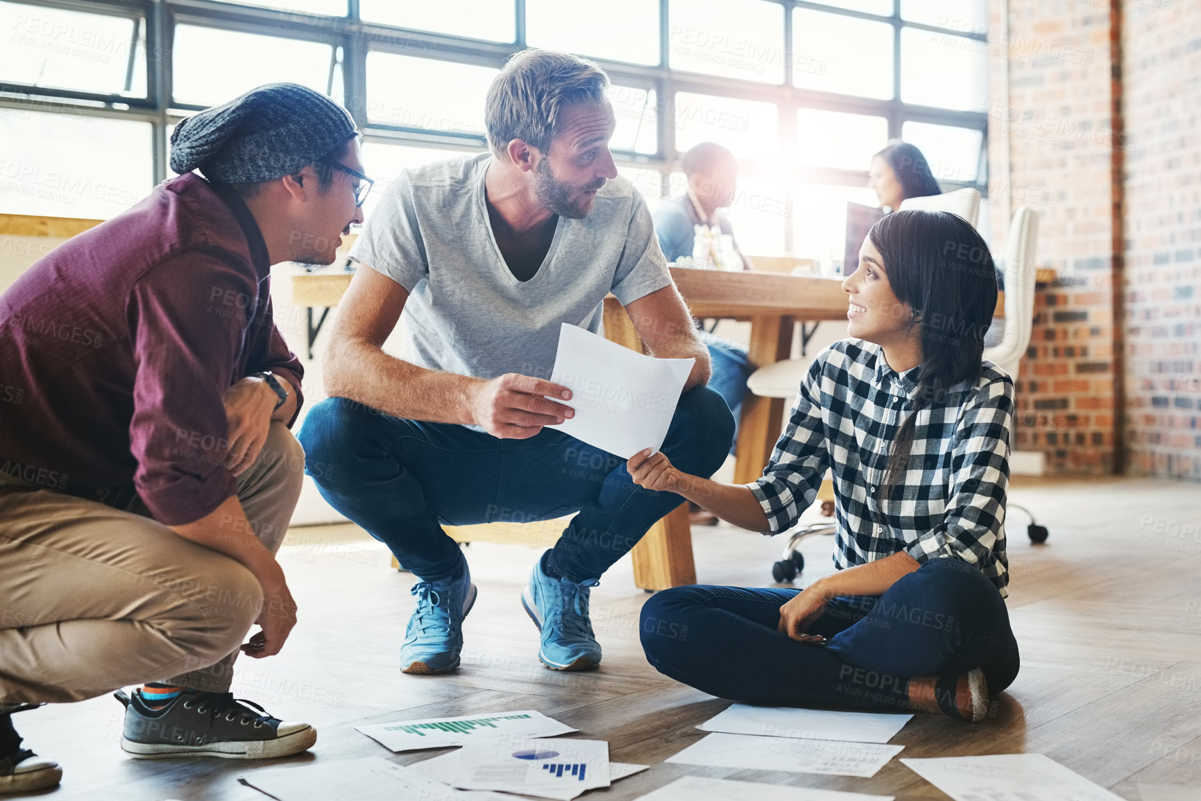 Buy stock photo Shot of a group of businesspeople brainstorming on the floor in an office