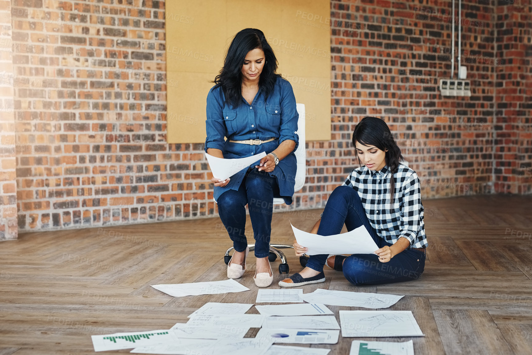 Buy stock photo Shot of two businesswomen brainstorming on the floor in an office