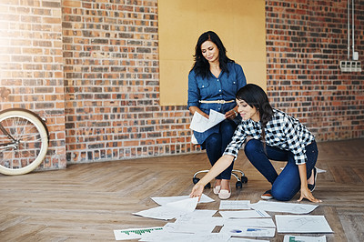 Buy stock photo Shot of two businesswomen brainstorming on the floor in an office