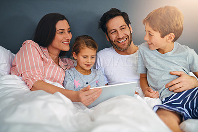 Buy stock photo Cropped shot of a young family using a tablet while chilling in bed together at home