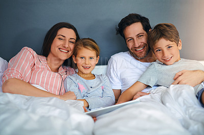 Buy stock photo Portrait of a young family using a tablet while chilling in bed together at home