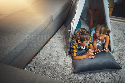 Buy stock photo High angle shot of an adorable little boy and girl using a tablet together while chilling in a homemade tent in the living room at home
