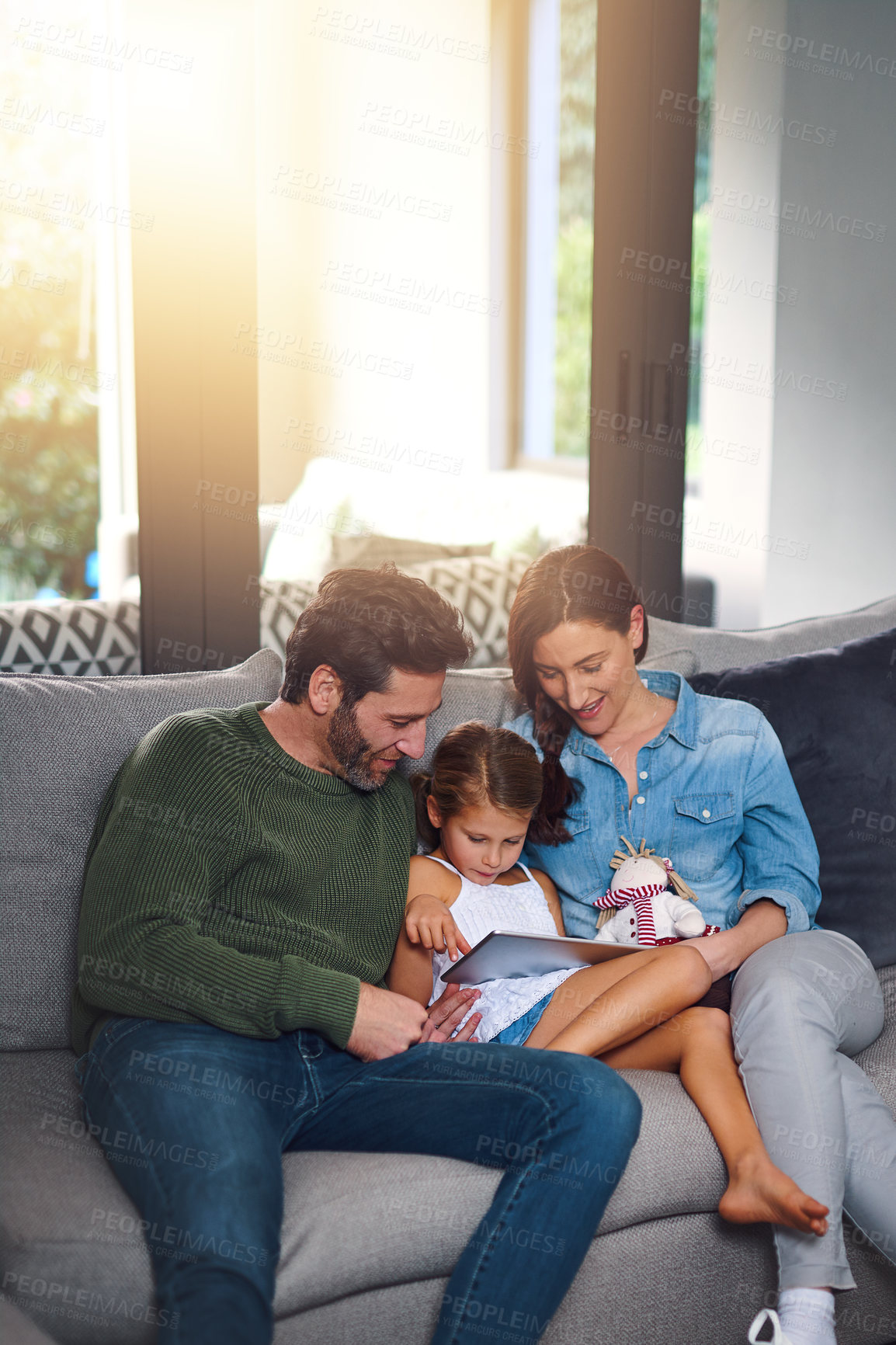 Buy stock photo Cropped shot of a young family using a tablet and chilling on the sofa together at home