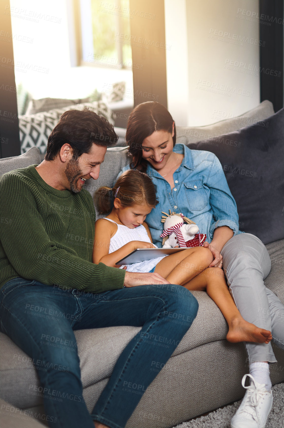 Buy stock photo Tablet, happy and child with parents on sofa in home streaming movie, show or series online. Relaxing, digital technology and girl kid with mother and father in living room playing game at house.