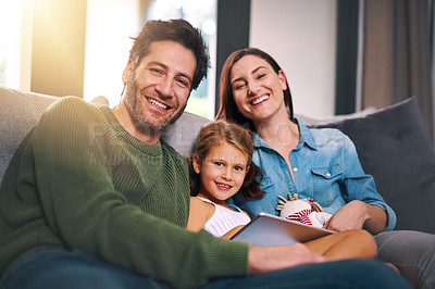 Buy stock photo Cropped shot of a young family using a tablet and chilling on the sofa together at home