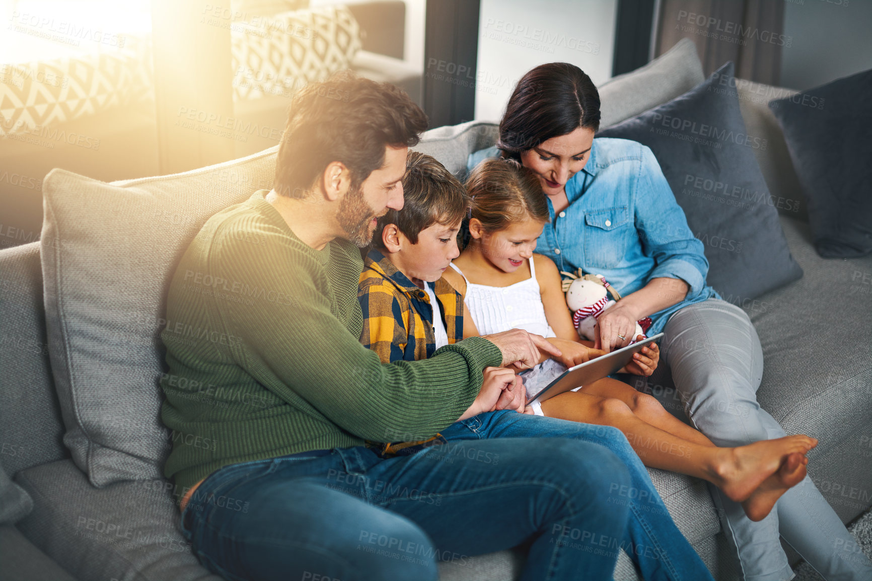 Buy stock photo Cropped shot of a young family using a tablet and chilling on the sofa together at home