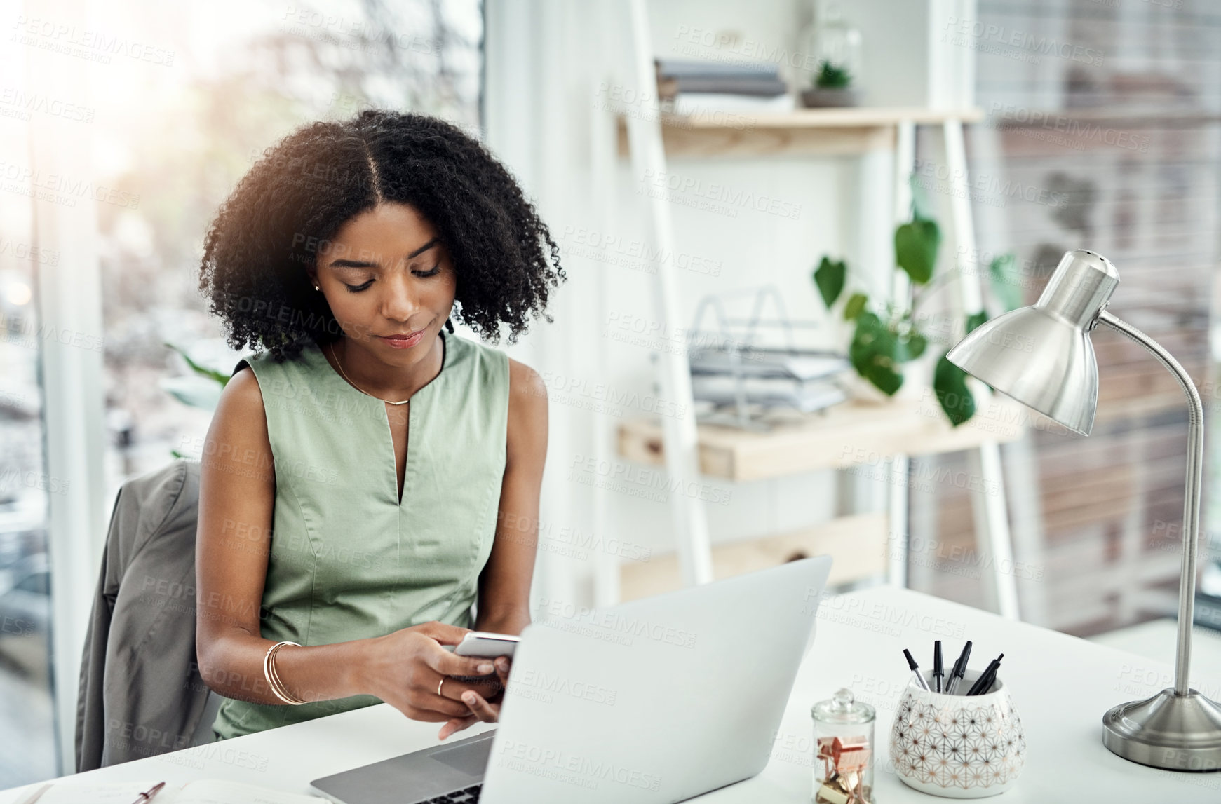 Buy stock photo Cropped shot of an attractive young businesswoman sending a text message while working at her desk in the office