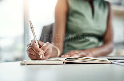 Buy stock photo Cropped shot of an unrecognizable young businesswoman writing in her diary while working in the office