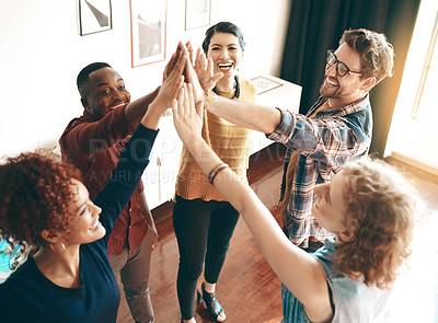 Buy stock photo Shot of a group of designers high fiving together in an office