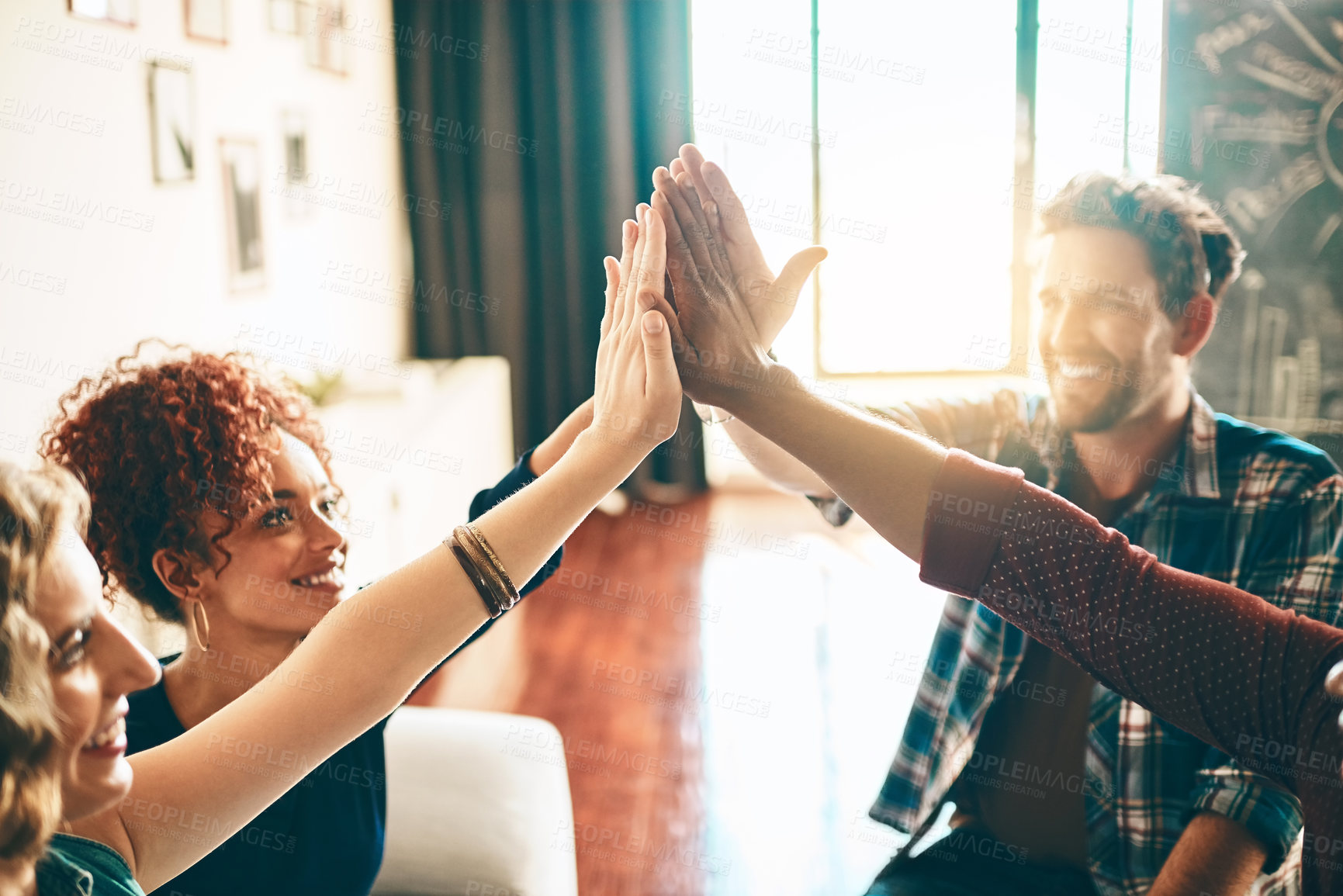 Buy stock photo Shot of a group of designers high fiving together in an office