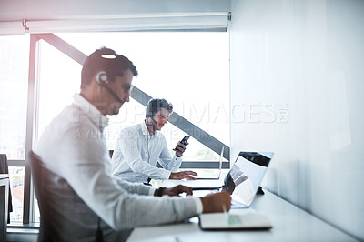 Buy stock photo Shot of two call centre agents working in an office