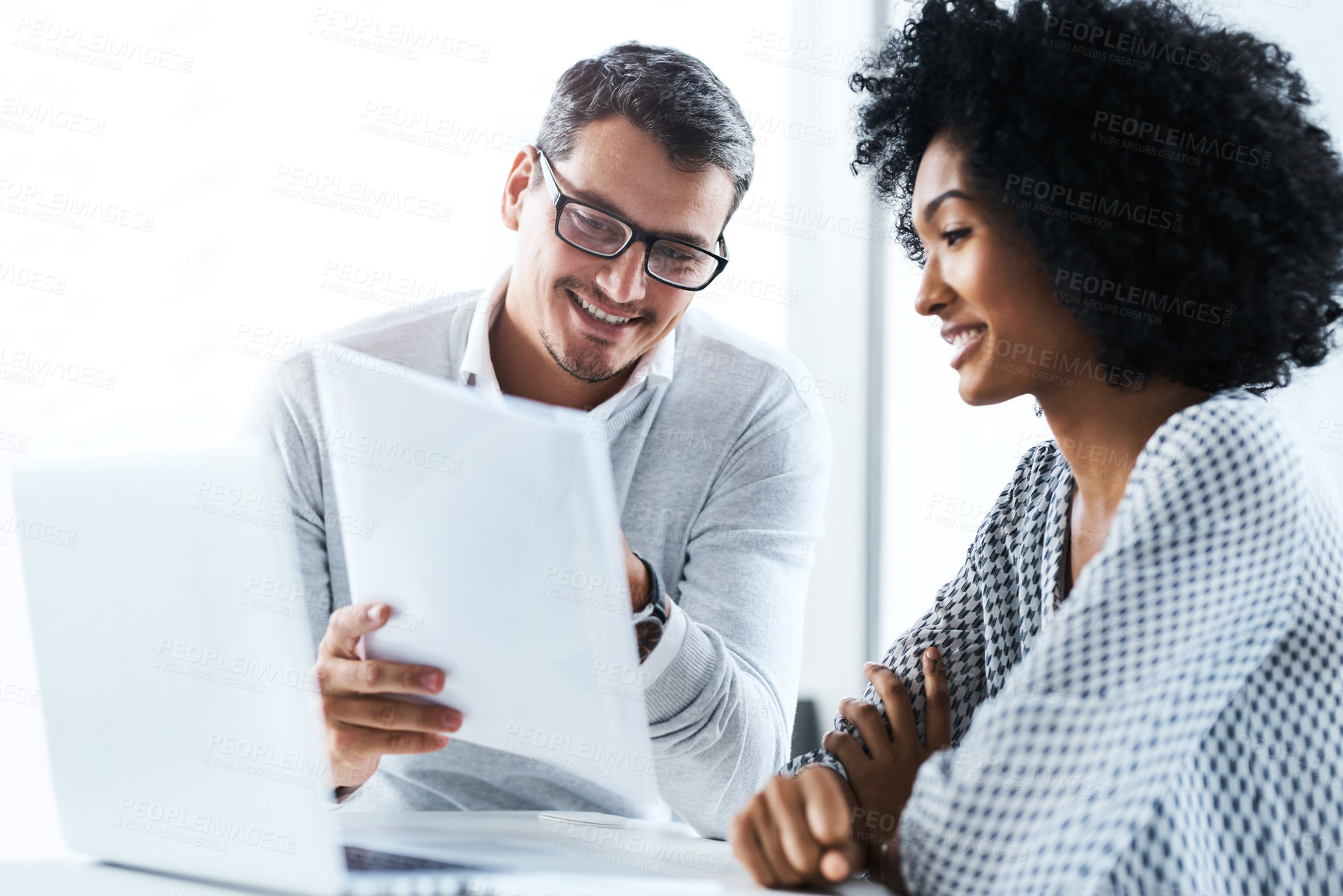 Buy stock photo Shot of two businesspeople going through some paperwork in an office