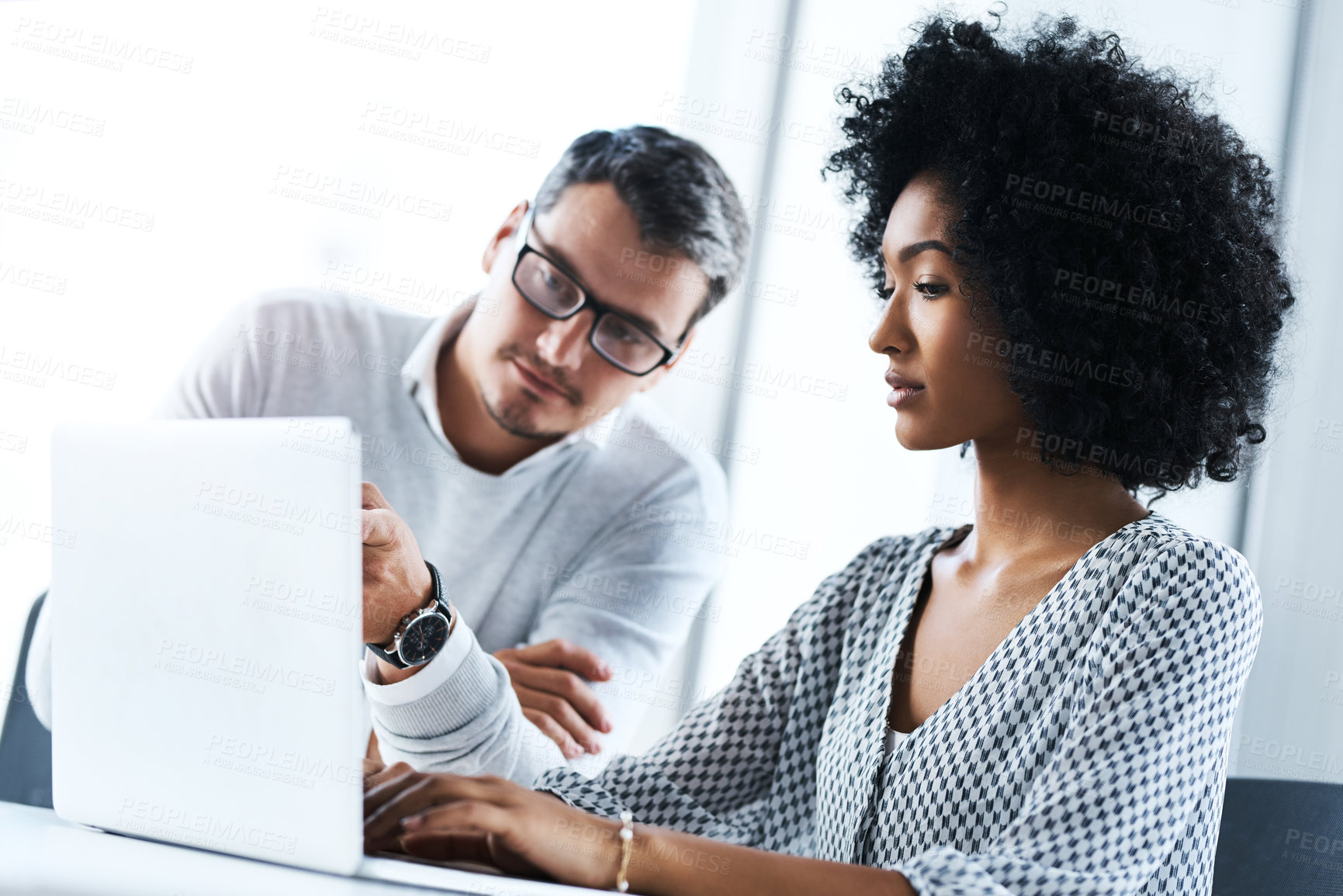 Buy stock photo Shot of two businesspeople working together on a laptop in an office