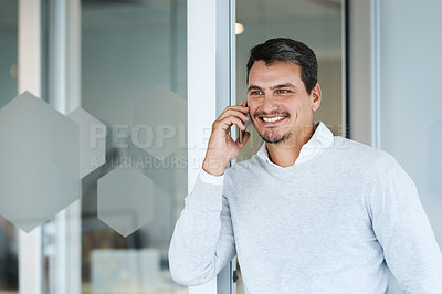 Buy stock photo Shot of a young businessman talking on a cellphone in an office